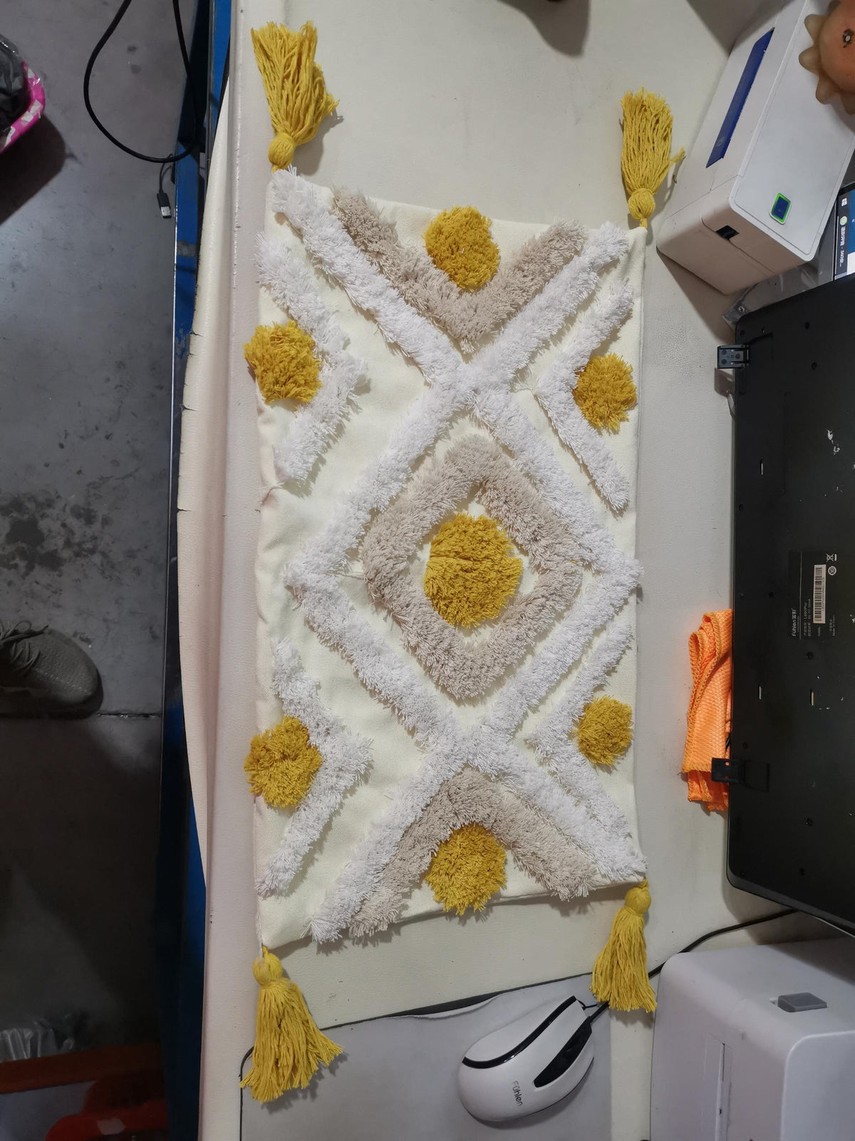 Decorative rug with yellow accents and tassels on a white floor.