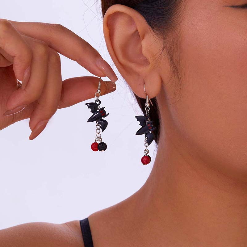 Close-up of a person wearing black and red beaded earrings with a blurred background