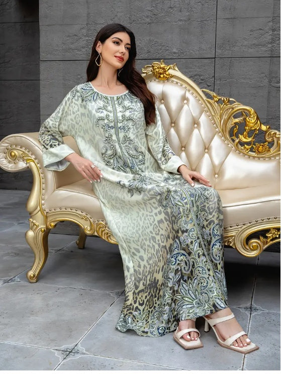 Woman in a patterned outfit sitting on an ornate couch against a gray wall.
