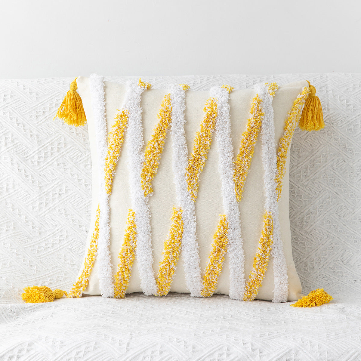 Decorative pillow with yellow tassels and embroidered patterns on a white background