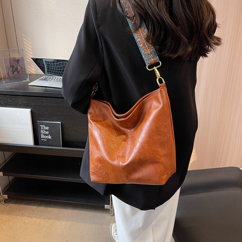 Person wearing a brown leather shoulder bag in an office setting