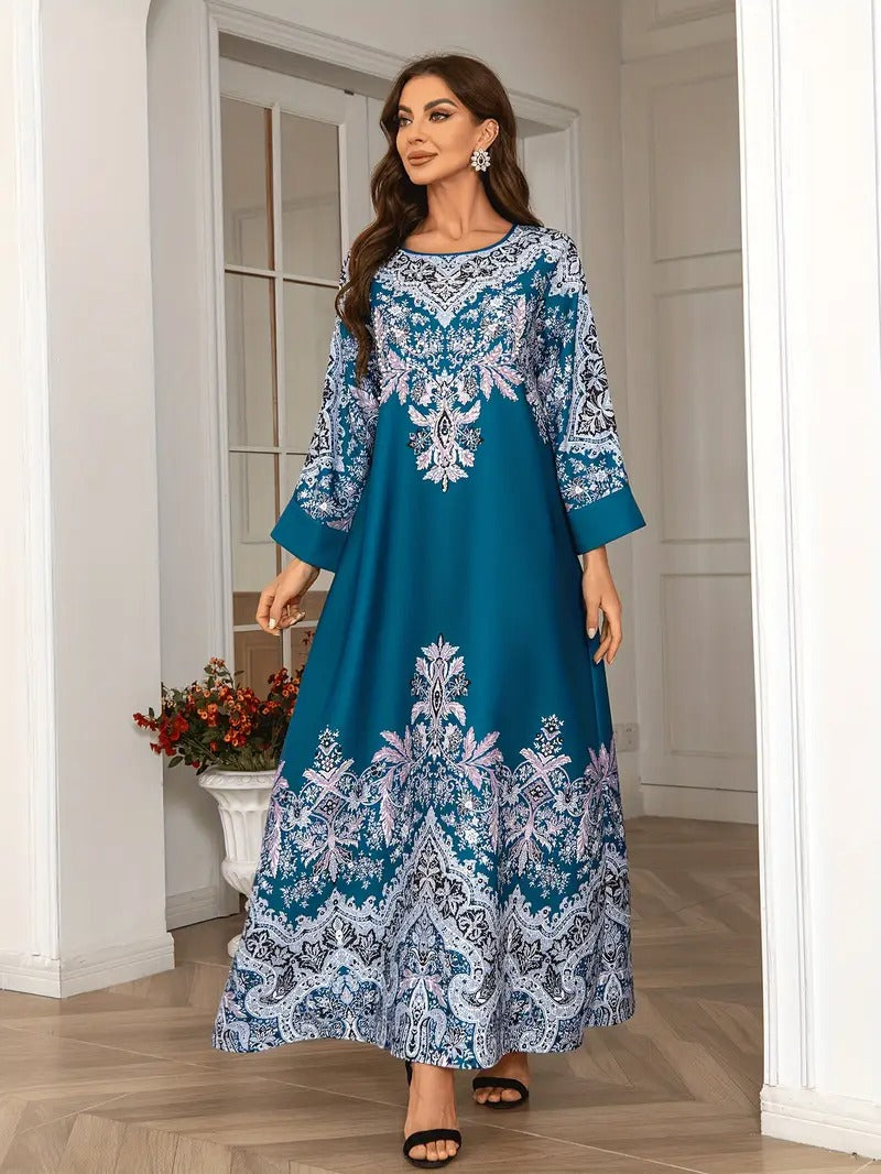 Woman wearing a blue and white patterned dress standing in a room with white walls and wooden floor.