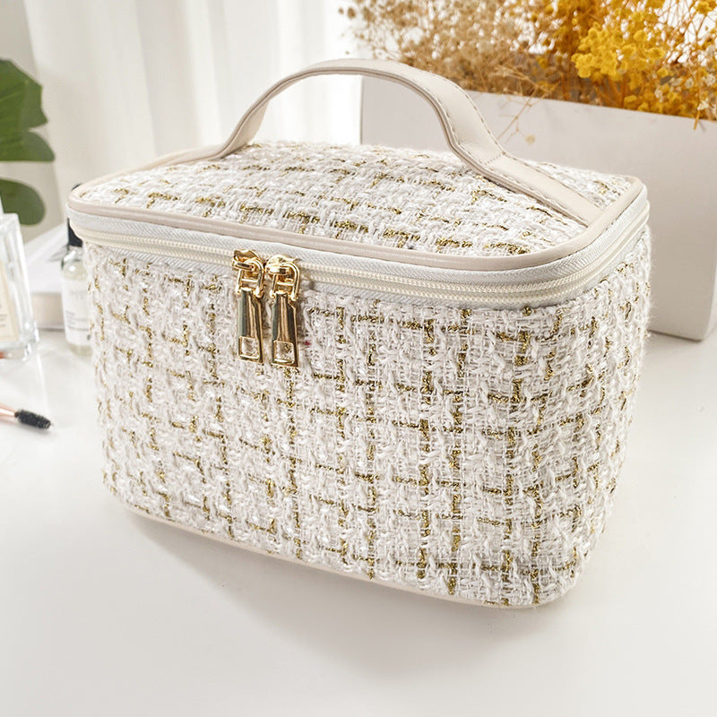 White and gold textured cosmetic bag on a light surface with a blurred background