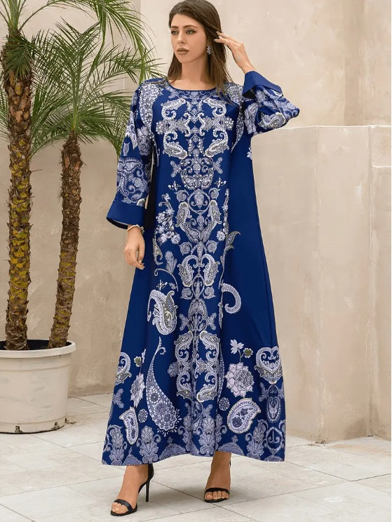 Woman wearing a blue and white patterned dress indoors with plants in the background