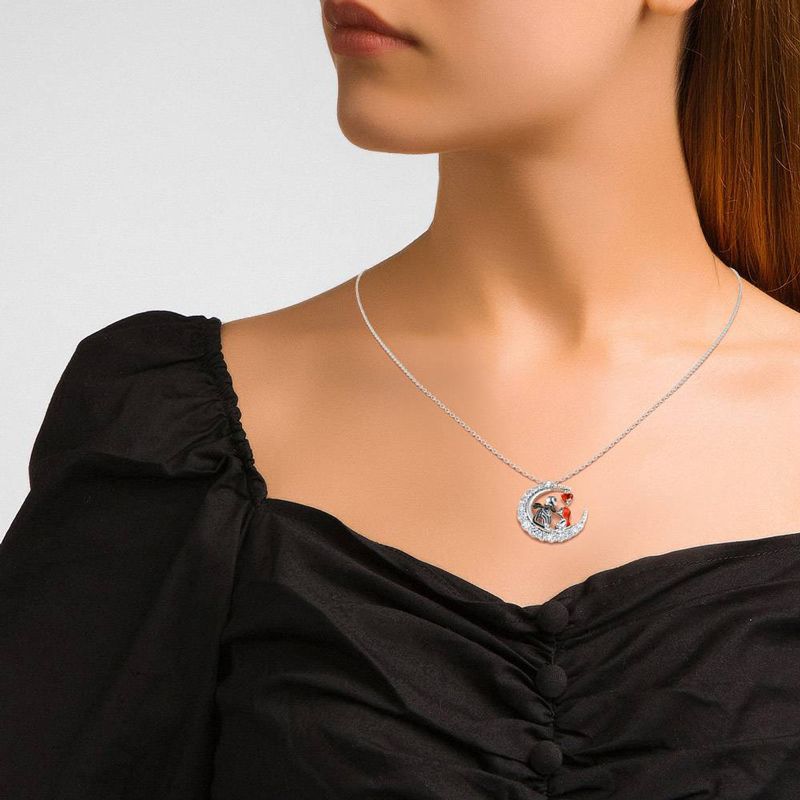 Woman wearing a black top with a silver necklace featuring a heart-shaped pendant.