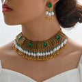 Ornate gold, green, and pearl necklace with matching earrings on a model.
