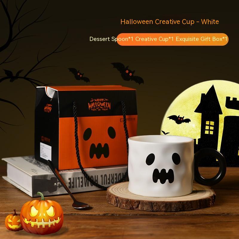 Halloween-themed cup with ghost design, pumpkin, and gift box on a wooden surface.