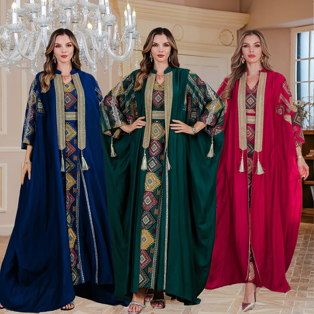 Three women wearing colorful abayas in a decorative room with a chandelier.