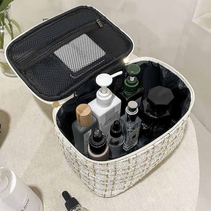 White textured cosmetic bag with beauty items in it, on a white surface.