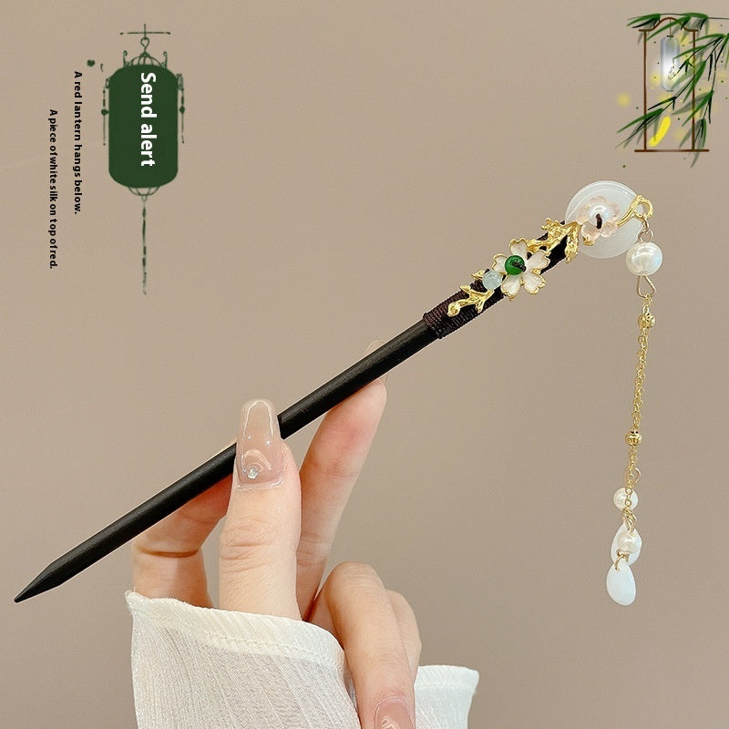 Decorative hairpin with beads held by a hand against a beige background