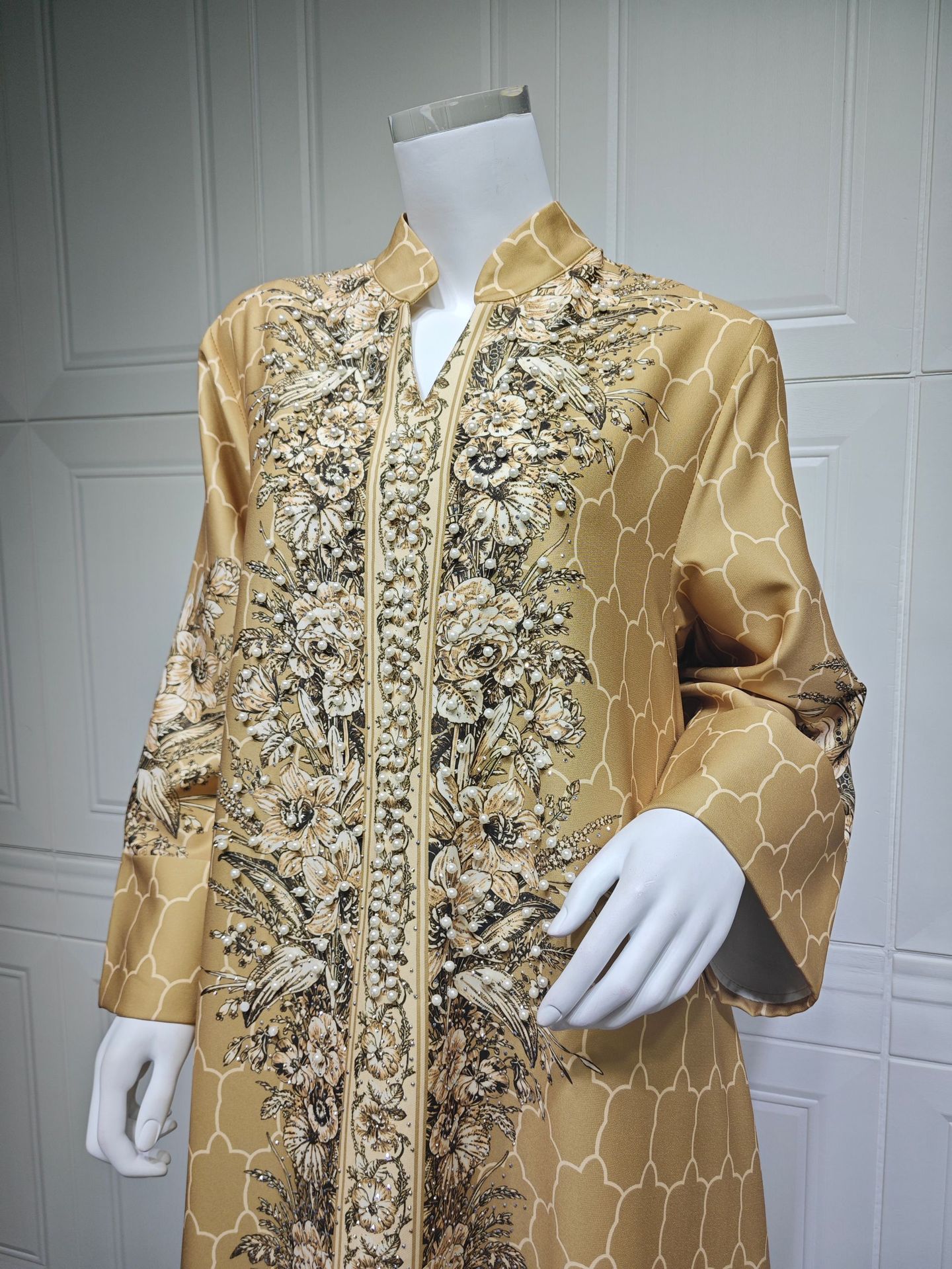 Gold embroidered jacket on a mannequin against a white paneled wall