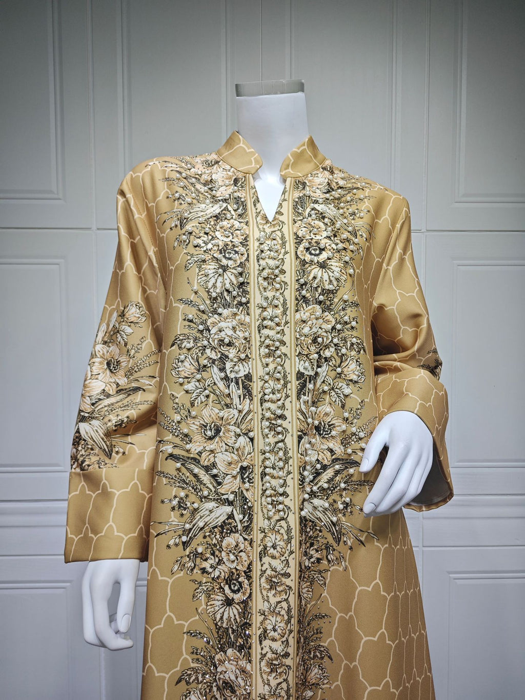 Gold embroidered jacket on a mannequin against a gray paneled wall