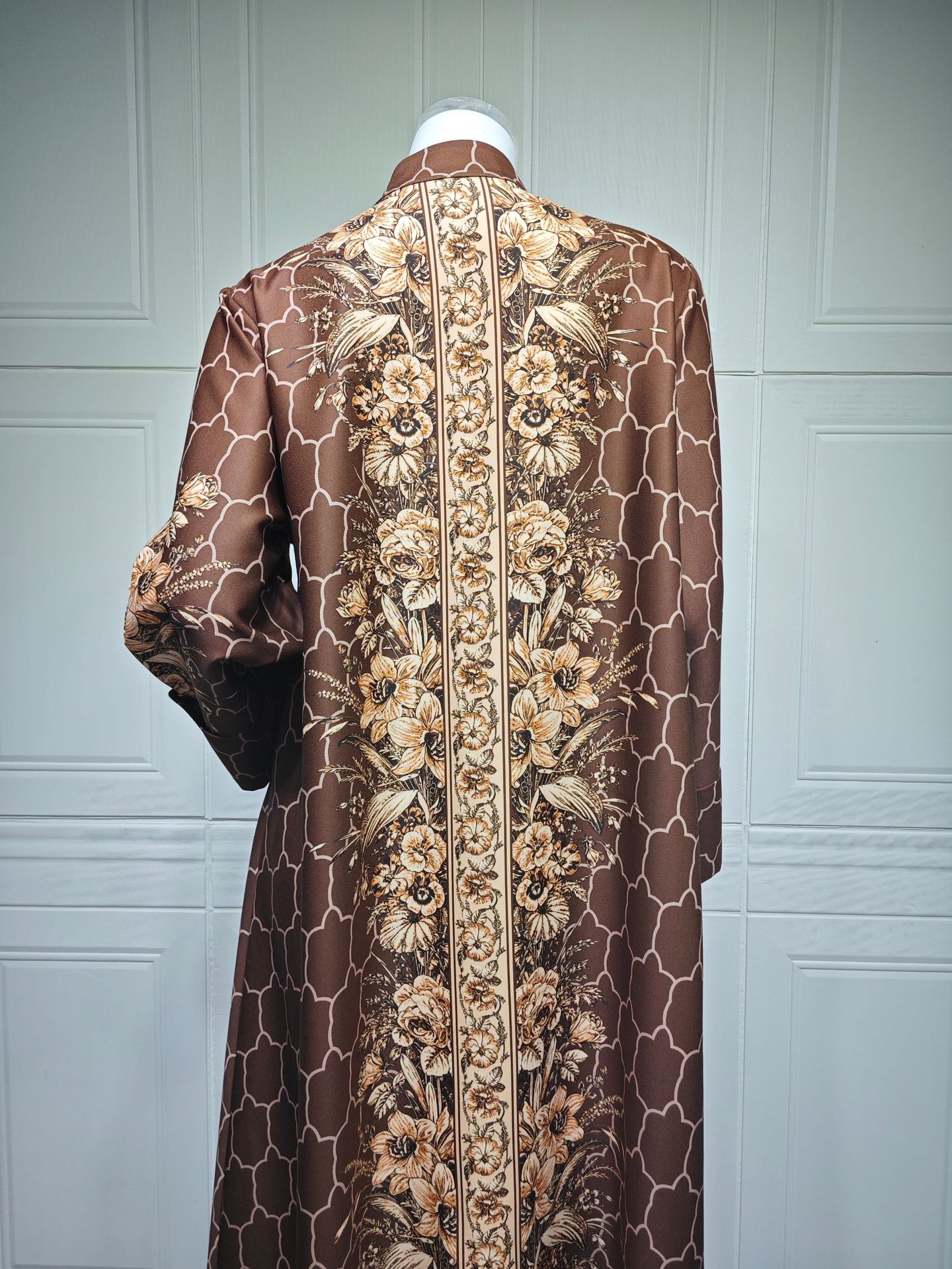 Brown floral patterned garment on a mannequin against a light blue paneled wall.