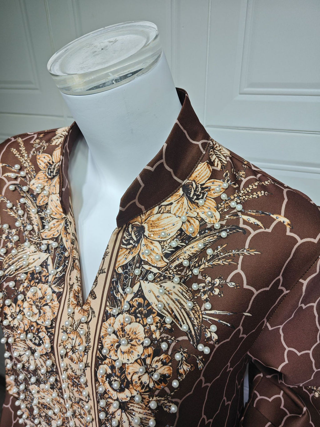 Mannequin wearing a brown floral patterned garment against a white background